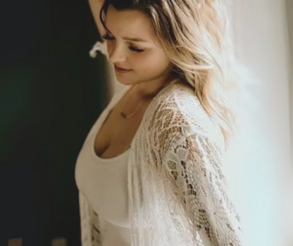 Bride wearing a white lace robe with a blurred background