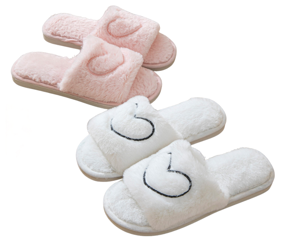 Pair of pink and white slippers with heart design on a white background