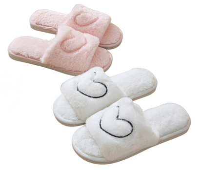 Pair of pink and white slippers with heart design on a white background