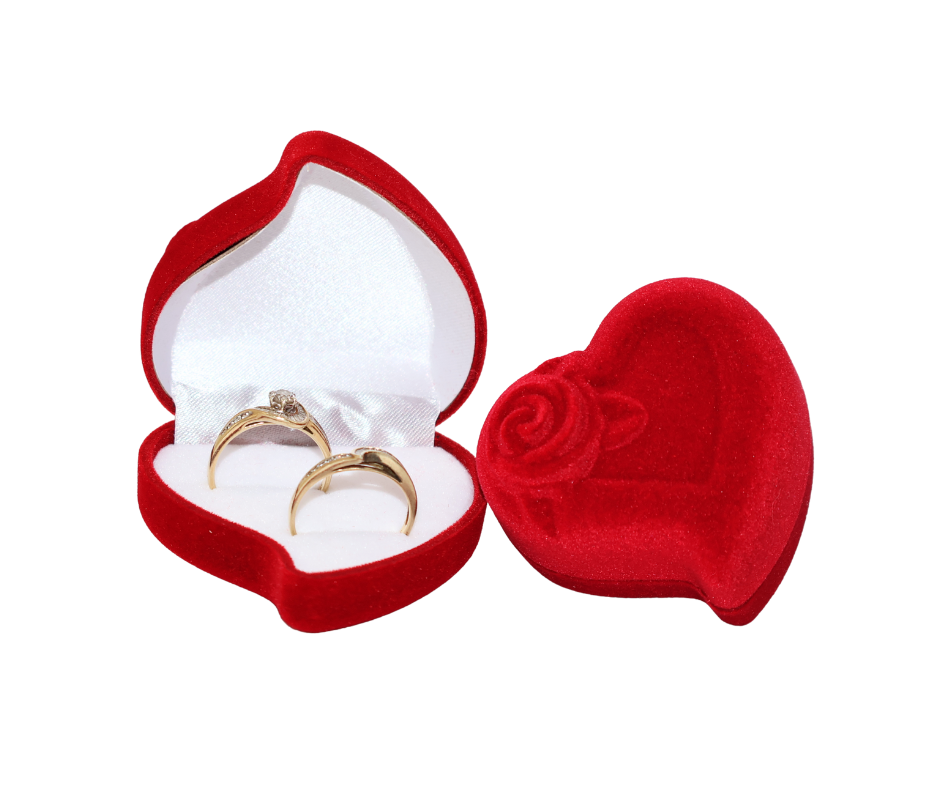 Red heart-shaped jewelry box with two gold rings on a white background