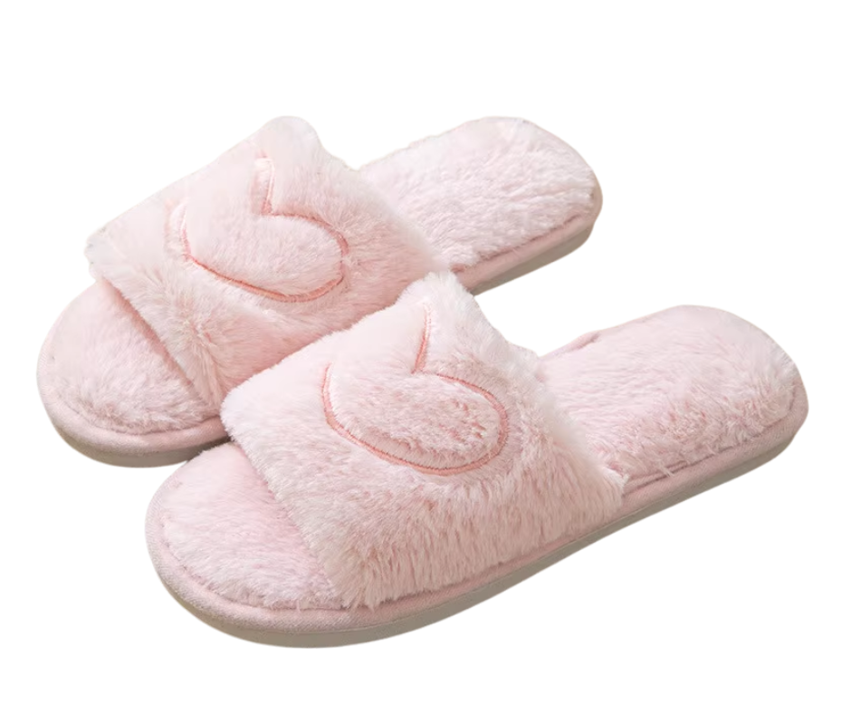 Pair of pink slippers with heart designs on a white background