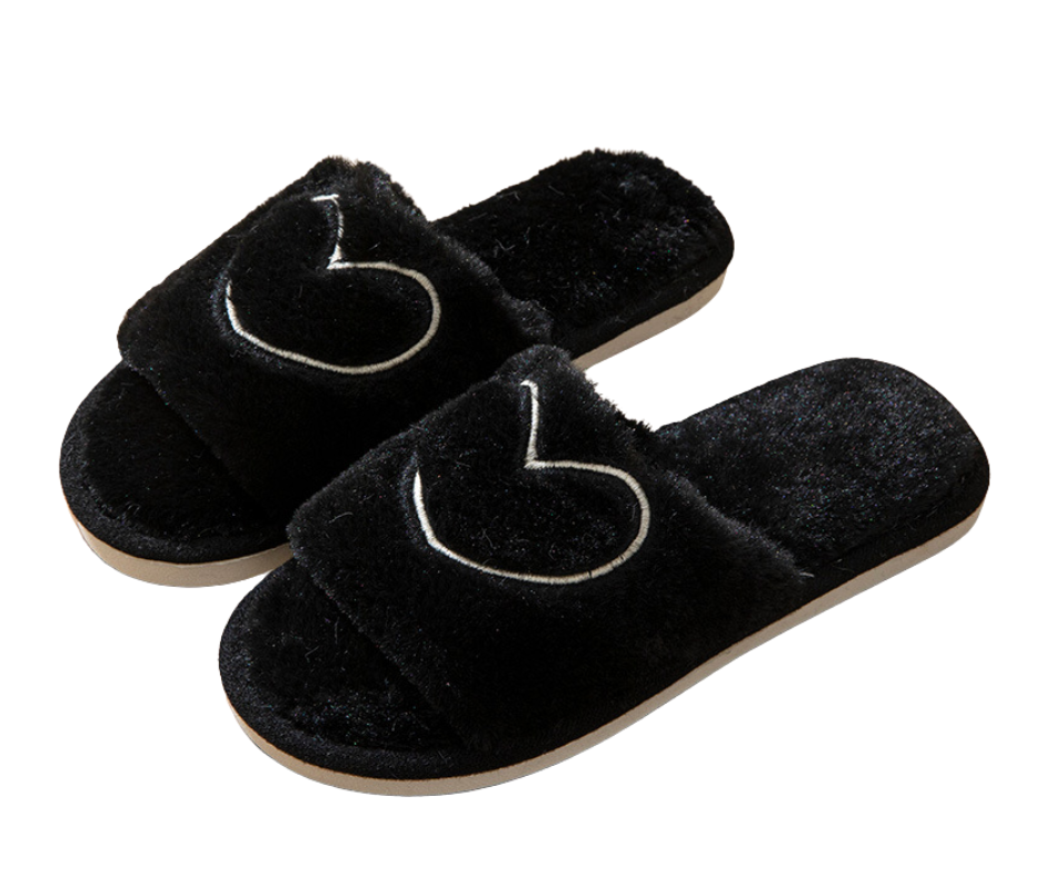 Pair of black slippers with heart designs on a white background