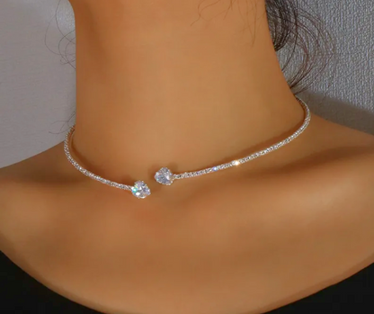 Choke with a heart-shaped clasp rhinestone worn by a person against a neutral background