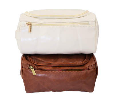 White  and brown toiletry bags stacked on a white background